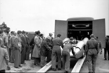 Großer Preis von England in Silverstone, 17.07.1954. Mercedes-Benz Formel-1-Rennwagen W 196 R mit Stromlinienkarosserie. Mercedes-Benz Lkw – Kastenwagen, Transporter der Rennabteilung.