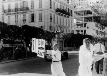 Großer Preis von Monaco (Europa) am 22. Mai 1955. Zeichengeber zeigt den jeweiligen Abstand an, im Hintergrund ein Mercedes-Benz Formel-1-Rennwagen W 196 R.