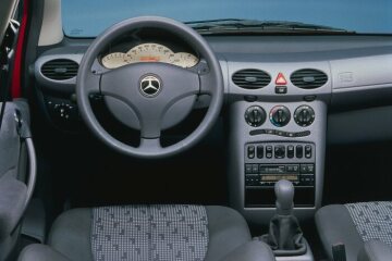 Mercedes-Benz A-Class, model series 168, 1997, equipment line Avantgarde, interior Rotterdam (608). Steering wheel with leather rim, gearshift lever strut in grey leather, instrument cluster with light-coloured dial face, instrument panel trim panels with single-tone soft finish. The slate-grey facings on the instrument panel and seats with fabric/leather upholstery accentuated the dynamic character of this model variant. The innovative seating allowed a total of 72 variations, making the interior extremely variable. Special equipment shown here: Air conditioner with activated charcoal filter (Code 580).