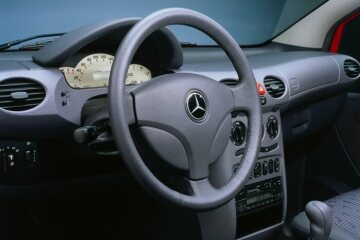 Mercedes-Benz A-Class, model series 168, 1997, equipment line Avantgarde, interior Rotterdam (608). Steering wheel with leather rim, gearshift lever strut in grey leather, instrument cluster with light-coloured dial face, instrument panel trim panels with single-tone soft finish. The slate-grey facings on the instrument panel and seats with fabric/leather upholstery accentuated the dynamic character of this model variant. The innovative seating allowed a total of 72 variations, making the interior extremely variable.