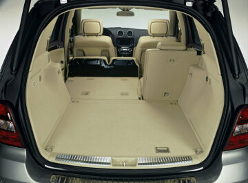 Mercedes-Benz M-Class, model series 164, 2005 version, studio shot, load compartment. Between 551 and 2050 litres (VDA measuring method) are available. The rear seats with backrests have a 63 : 37 folding split. The rear seat cushions can be swivelled into a vertical position behind the backrests of the front seats. The headroom under the open tailgate is 1.9 metres. The load can be easily secured to six lashing eyes and small items fit into the side stowage compartment. Available as special equipment: the EASY-PACK load-securing kit with load rails and removable rear seats as well as hydraulic operation of the tailgate.