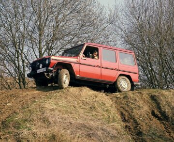 Mercedes-Benz 280 GE, Station-Wagen lang, Geländewagen, Baureihe 460 GE 28, Version 1981. Reihensechszylinder-Einspritz-Benzinmotor M 110, 2.746 cm³, 115 kW/156 PS (ohne Katalysator). Serienlackierung Karminrot (RAL 3002), Halogen-Nebelscheinwerfer, Reserverad am Heck (Sonderausstattungen). Zu den unverkennbaren optischen Merkmalen der G-Reihe zählen gerade Linien, ausgewogene Proportionen der Flächen, kurze Überhänge sowie eckige Kotflügel, die eine gute Sicht auf die Fahrbahn zulassen und zielgenaues Fahren erleichtern - auch im extremen Geländeeinsatz mit starker Achsverschränkung.