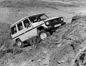 Mercedes-Benz 300 GD, Station-Wagen lang, Geländewagen, Baureihe 460, Version 1979, Serienlackierung Weizengelb (DB 1681), Interieur Stoff braun. Mit einem Steigvermögen von bis zu 80 Prozent und seitlicher Fahrstabilität selbst noch bei 54 Prozent Schräglage bezwingen die Typen 230 G, 240 GD, 280 GE und 300 GD souverän auch schwierigste Fahrsituationen im Gelände. Dazu tragen die Bodenfreiheit von 21 Zentimetern, die Böschungswinkel von 36 Grad vorn und 27 Grad hinten, die Wattiefe von bis zu 60 Zentimetern und eine Achsverschränkung von 260 Millimetern (mit Schraubenfedern) bei.