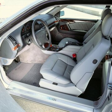 Mercedes-Benz 500 SEC, 600 SEC (from 06.1993: S 500 Coupé, S 600 Coupé), model series 140, 1992 version, brilliant silver metallic. The interior is trimmed with burr walnut as standard. The leather upholstery, shown here in grey, is available as an option for the 600 SEC/S 600 Coupé at no extra charge (velour as standard). Driver's seat with fore/aft, height and inclination adjustment for seat cushion and backrest, additional adjustability for seat cushion length and lumbar support. Electric seat adjustment unit as standard, with memory for 3 positions (special equipment in the 500 SEC/S 500 Coupé, standard equipment in the 600 SEC/S 600 Coupé), vacuum-controlled backrest lock. Seat contours with a clearly pronounced bucket seat character. Height-adjustable head restraints, held from below in a leather-covered, U-shaped decorative clasp and set into the upholstered surfaces on both sides.