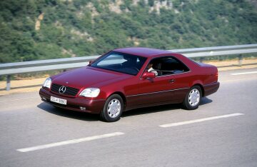 Mercedes-Benz 500 SEC (from 06.1993: S 500 Coupé), model series 140, 1992 version. Front section characterised by the SL radiator grille, coupé character without continuous B-pillars, rear lights in integrated design. V8 spark-ignition engine M 119 with 4973 cc and 235 kW/320 hp. Almandine red metallic (metallic paintwork at extra charge), velour upholstery (standard) in black (leather as option). Electric sliding sunroof (standard equipment), headlamp wiper system and 8-hole forged light-alloy wheels (both special equipment).