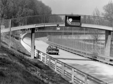 Einfahrbahn in Untertürkheim, 1967
Bildtext: Die Einfahrt in die Steilwand des Untertürkheimer Versuchsgelände der Daimler-Benz AG. Die obere schnelle Kurve ist durch ein Warnsignal an der über die Bahn führende Brücke gesichert. Das Signal leuchtet auf, solange die Kurve von einem durchfahrenden Fahrzeug besetzt ist.