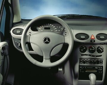Mercedes-Benz A-Class, model series 168, 1997, interior, equipment line Elegance (steering wheel with leather rim and dark dial face), leather upholstery in slate grey (208) as special equipment. The design of the instrument panel with the new three-spoke steering wheel (diameter 370 millimetres) incorporated the latest ergonomic findings. The controls were easily accessible to the driver or front passenger. The needles of the speedometer, rev counter and fuel gauge only became visible when the ignition was switched on, and were transparent. The information on the centrally positioned multi-information display was therefore visible at all times. Air conditioner (special equipment, Code 580).