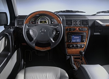 Mercedes-Benz G 55 AMG Off-Roader W 463 model series, 2004: With the multifunction steering wheel, here in leather-wood design, information can be called up on the display of the instrument cluster, comfort settings can be made, radio and navigation can be operated without taking your hands off the steering wheel. In the middle of the car, the console with the controls of the climate control and the switch groups for all-wheel drive or seat heating.
