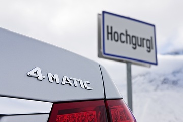 Mercedes-Benz E 350 4MATIC Limousine, Baureihe 212, Version 2009, Ausstattungslinie AVANTGARDE, Iridiumsilber Metallic, Leichtmetallräder im 5-Doppelspeichen-Design. Typenzeichen am Heckdeckel rechts und LED Leuchten, Ortseingang Hochgurgl/Österreich.