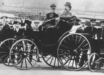 Benz Victoria mit Bertha und Carl Benz bei einem Ausflug nach Worms. Der Benz Victoria ist das erste Automobil mit der von Benz patentierten Achsschenkellenkung, die erst dessen Entwicklung ermöglicht.