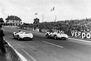 Großer Preis von Frankreich 1954: Beim Grand Prix von Frankreich liefern sich Karl Kling und Juan Manuel Fangio ein packendes Duell, bei dem die Führungsposition dauernd wechselt. Oft fahren die beiden Konkurrenten aus dem gleichen Rennstall Rad an Rad nebeneinander her.