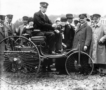 Carl Benz in späteren Jahren auf seinem ersten Patent-Motorwagen vom Typ I.
