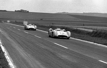 Großer Preis von Frankreich in Reims, 4. Juli 1954. Doppelsieg in Reihenfolge: Juan Manuel Fangio (Startnummer 18) und Karl Kling (Startnummer 20) beide auf Mercedes-Benz Formel-1-Rennwagen W 196 R mit Stromlinienkarosserie übernehmen vom Start an die Führung.
