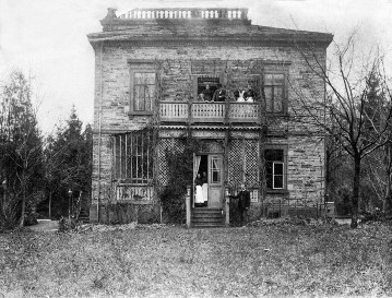 Haus der Familie Daimler in Cannstatt, Taubenheimstraße. Blick vom Garten auf  das Haus. In der Mitte auf dem Balkon: Gottlieb Daimer, daneben vermutlich Ehefrau Lina Daimler mit Hund Bello, Hausangestellte.Unten am Balkon rechts vermutlich Paul Daimler, Hausangestellte. ca. 1895