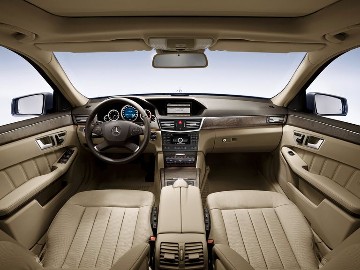 Mercedes-Benz E-Class Saloon, 212 series, interior. The designers and engineers paid great attention to detail during the development of the interior. Four handcrafted, excellently finished fine wood veneers were available, also trim in high-grade aluminium for customers with a sporty inclination. Thanks to larger interior dimensions, the spaciousness, seating comfort and ergonomics of the Mercedes-Benz E-Class were outstanding. Example vehicle with ELEGANCE equipment line, interior in mocha brown/almond beige, interior trim in open-pore brown ash wood (special equipment), 4-spoke multifunction steering wheel.