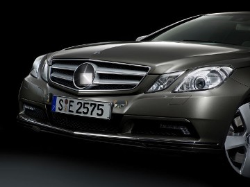 Mercedes-Benz E-Class Coupé, model series 207, 2009 version. 4-eye face with projection headlamps (Light package as special equipment), integrated Mercedes-Benz star in radiator grille with 2 louvres, exclusive light-alloy wheels, here in 5-spoke design. DISTRONIC PLUS including BAS PLUS (Brake Assist) and PRE-SAFE Brake (special equipment) with the sensors on the radiator grille.
