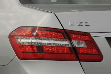 Mercedes-Benz E 63 AMG Limousine, Baureihe 212, 2009, Typenzeichen am Heckdeckel, linke Seite, AMG Spoilerlippe, LED Leuchten.